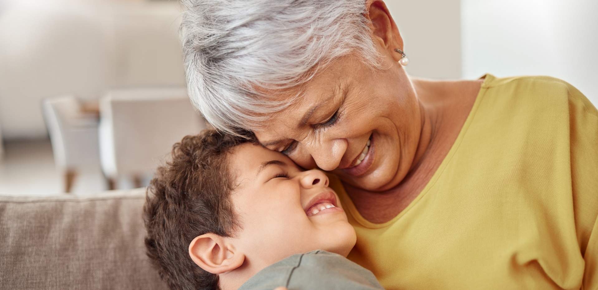 Older woman smiling while cuddling a young boy on a couch